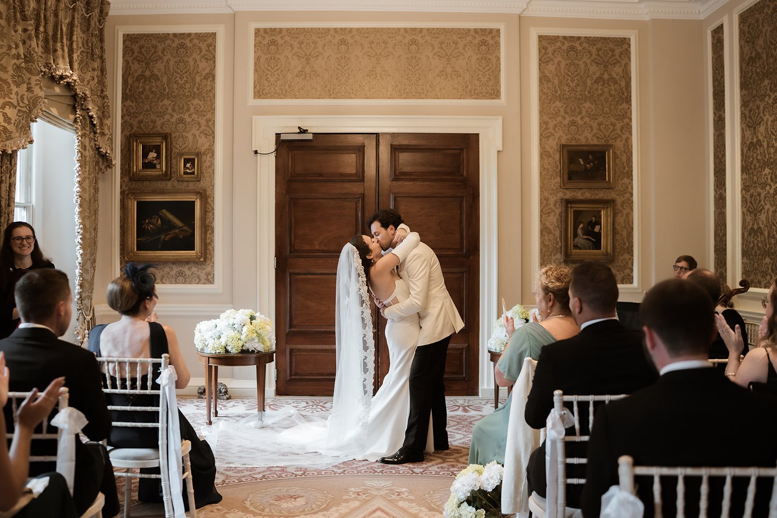 A bride and groom kiss in front of their wedding guests