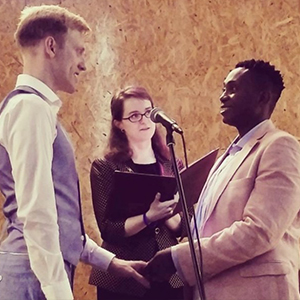 Stephanie Kendrick reads from her ceremony book, next to the two grooms
