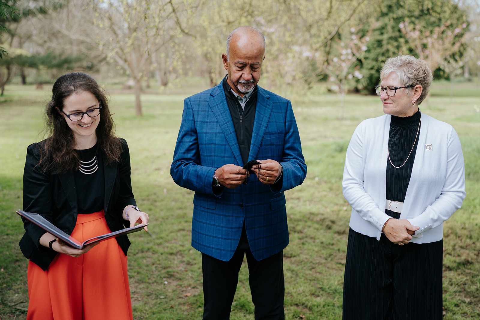 Steph reads from her ceremony binder, next to a man in a suit and a smart woman